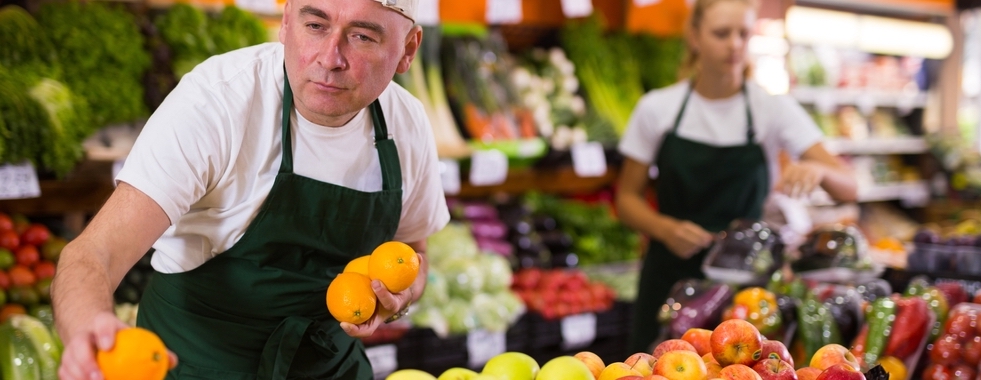 Workers replenish orange display in a supermarket